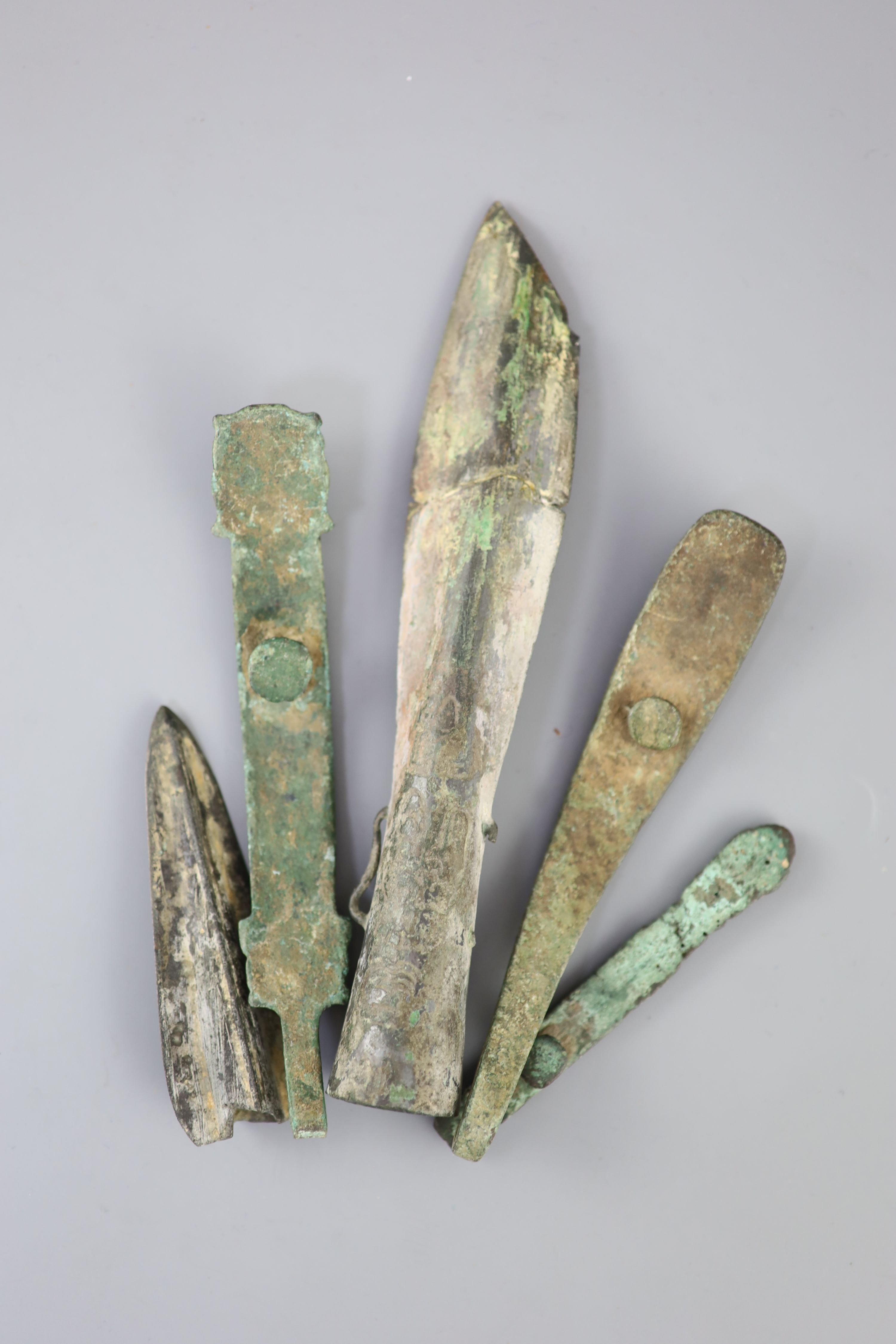 Three Chinese archaic bronze belt hooks and two spear heads, Warring States / Han dynasty